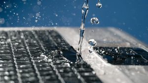 A stream of water pours on the laptop keyboard.